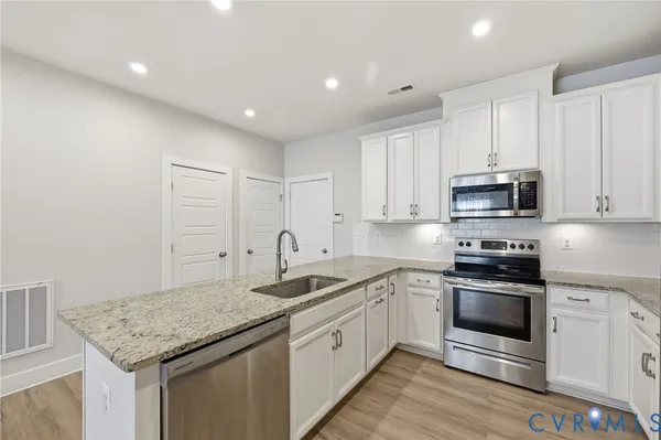 a kitchen with granite countertop stainless steel appliances and white cabinets