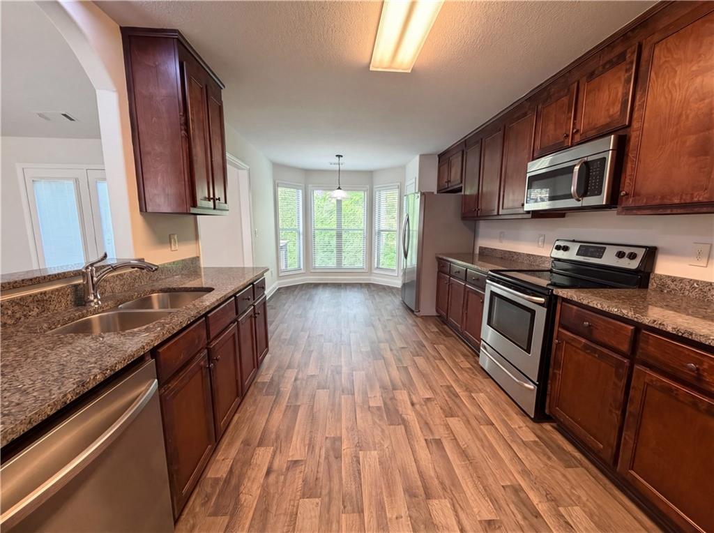 1948 Paynes Point Winder, GA 30680 - Photo 9 of 22 a kitchen with stainless steel appliances granite countertop wooden cabinets a stove top oven a sink and dishwasher with wooden floor