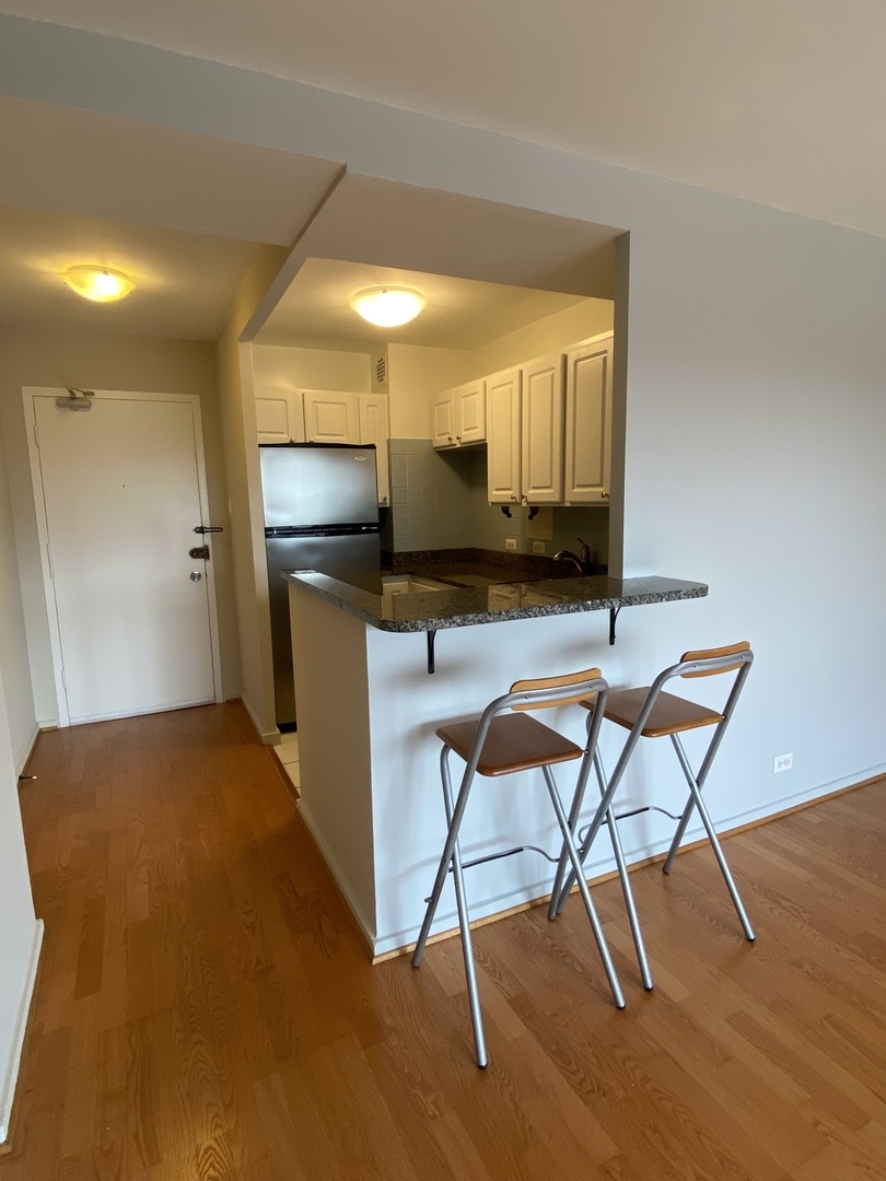 2909 North Sheridan Road, Unit 805 Chicago, IL 60657 - Photo 4 of 39 a kitchen with a table chairs refrigerator and microwave