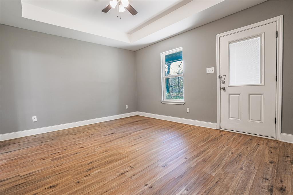 900 Cedar Street Commerce, TX 75428 - Photo 3 of 13 Entrance foyer featuring a tray ceiling, baseboards, light wood finished floors, and a ceiling fan