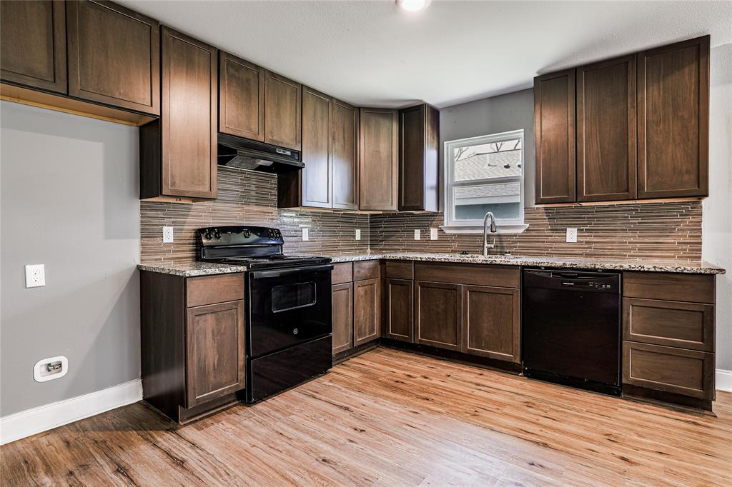 900 Cedar Street Commerce, TX 75428 - Photo 5 of 13 Kitchen featuring baseboards, under cabinet range hood, a sink, light stone counters, and black appliances
