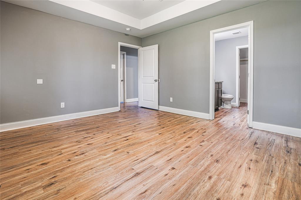900 Cedar Street Commerce, TX 75428 - Photo 6 of 13 Unfurnished bedroom featuring connected bathroom, baseboards, visible vents, and light wood-style flooring