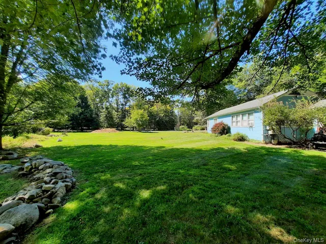 a view of a white house in a big yard with large trees
