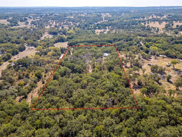 an aerial view of residential houses with outdoor space and trees