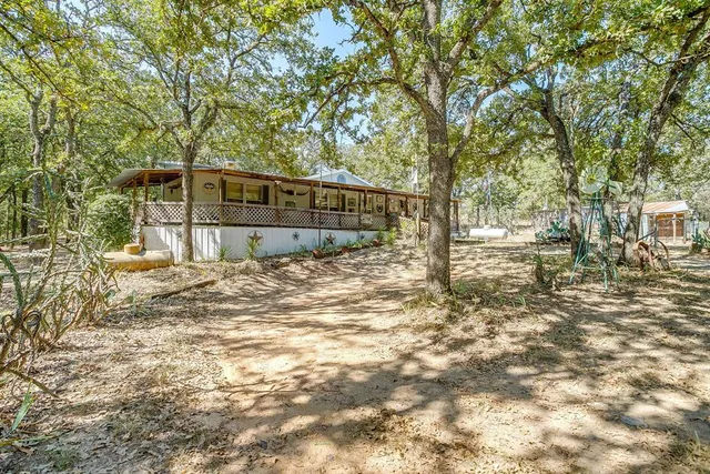 a view of a house with backyard and trees