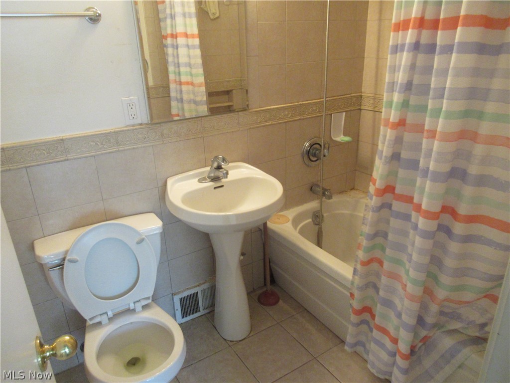 6033 Randy Road Bedford Heights, OH 44146 - Photo 16 of 19 Bathroom featuring a pedestal sink, toilet, and built-in bathtub with shower fixtures