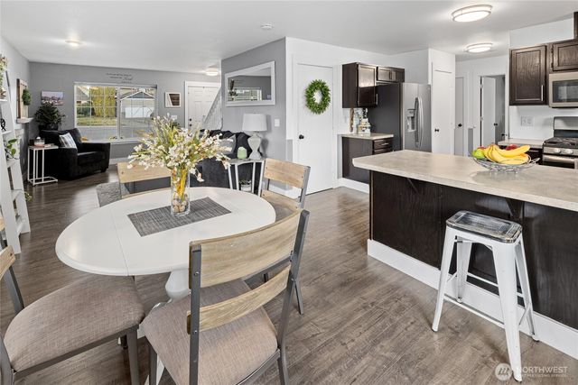 a kitchen with stainless steel appliances kitchen island granite countertop a dining table chairs and a refrigerator