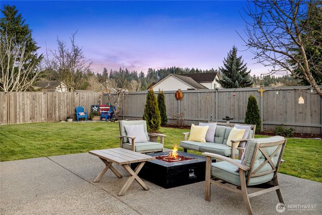 a view of a backyard with couches table and chairs with plants and wooden fence