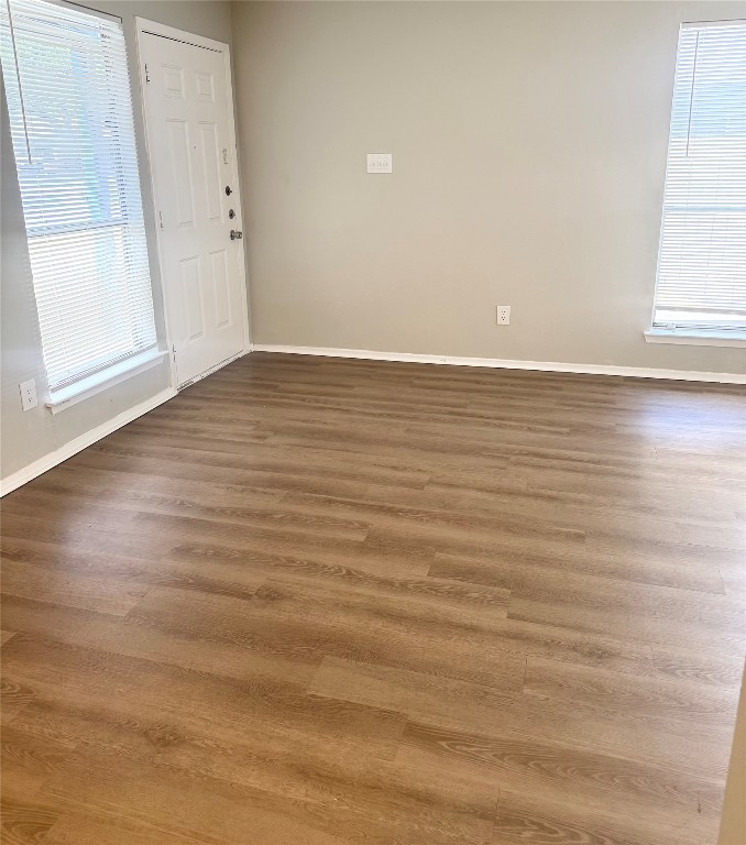 5011 Copperbend Boulevard, Unit A Austin, TX 78744 - Photo 2 of 18 an empty room with wooden floor and windows with curtains