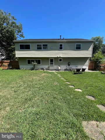 a backyard of a house with plants and large tree