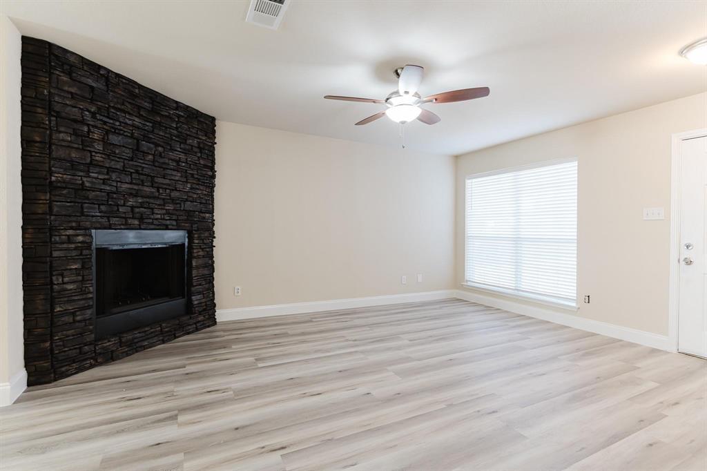 2109 Windjammer Way Rowlett, TX 75088 - Photo 2 of 21 Unfurnished living room with light wood-style floors, a glass covered fireplace, and ceiling fan
