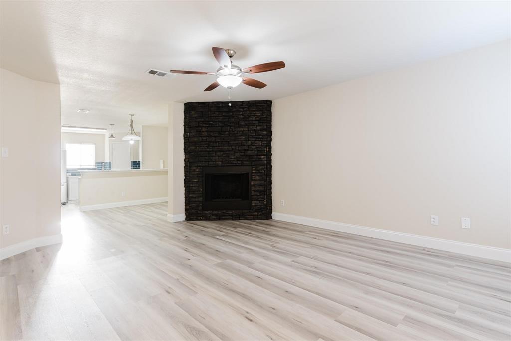 2109 Windjammer Way Rowlett, TX 75088 - Photo 3 of 21 Unfurnished living room with light wood-type flooring, a fireplace, and ceiling fan