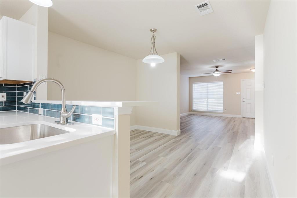 2109 Windjammer Way Rowlett, TX 75088 - Photo 21 of 21 Kitchen featuring decorative light fixtures, backsplash, light wood finished floors, white cabinetry, and open floor plan