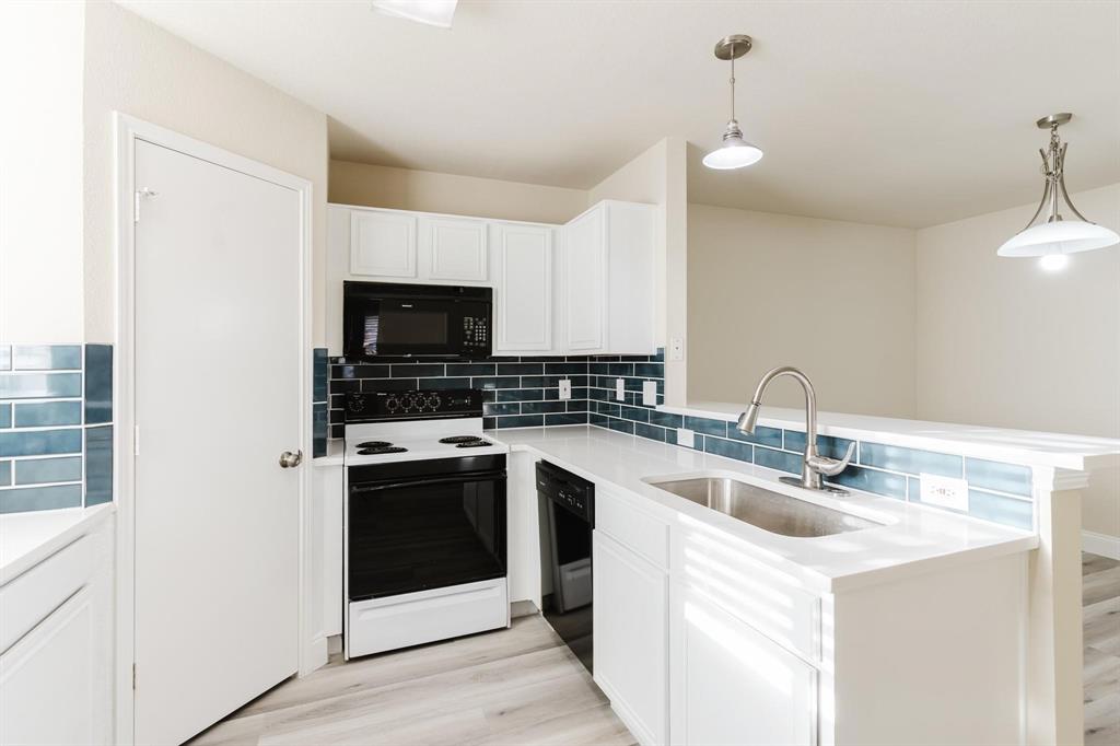 2109 Windjammer Way Rowlett, TX 75088 - Photo 6 of 21 Kitchen with black appliances, tasteful backsplash, decorative light fixtures, and white cabinets