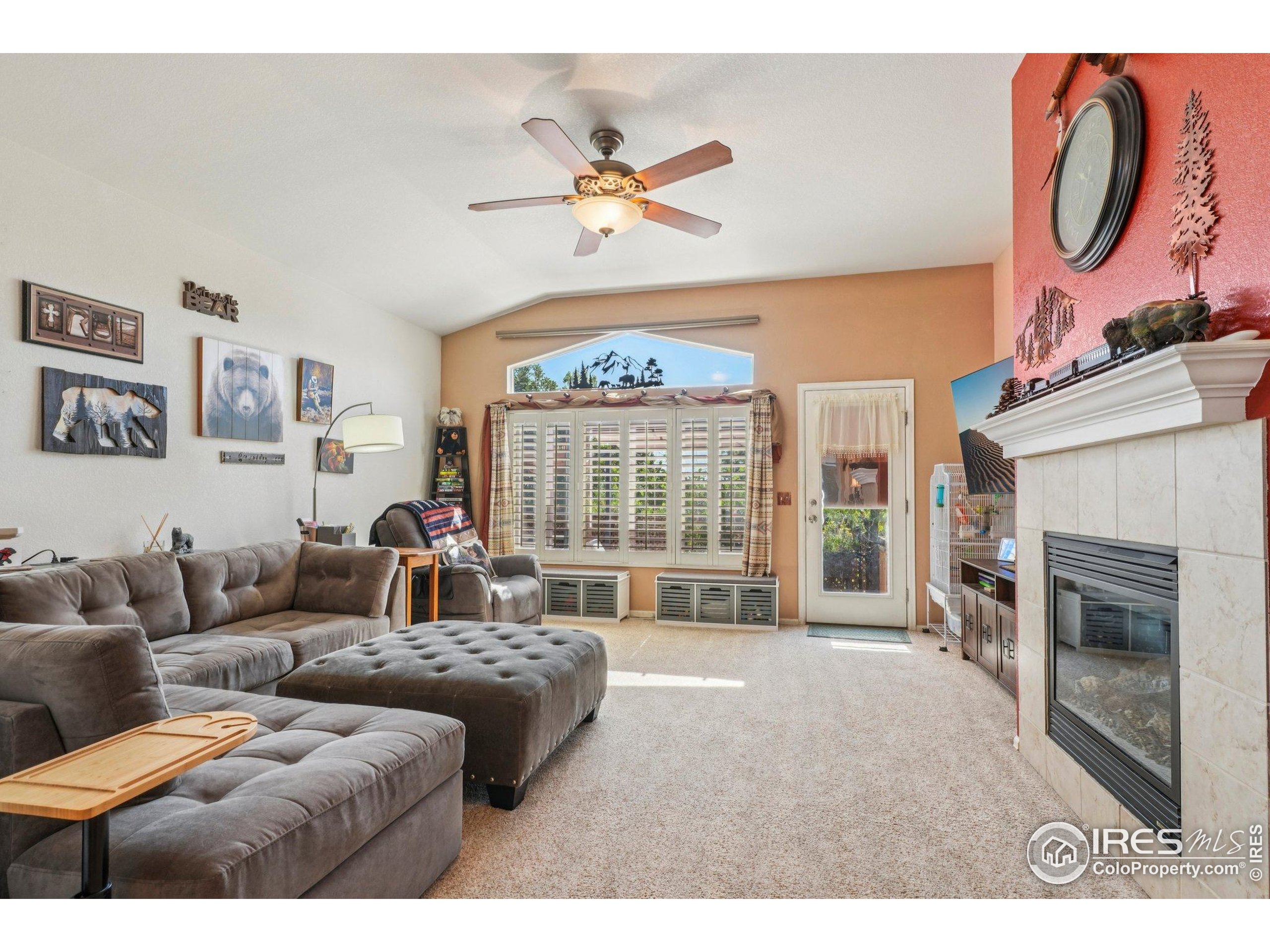 256 Homestead Way Brighton, CO 80601 - Photo 13 of 42 a living room with furniture a fireplace and a large window