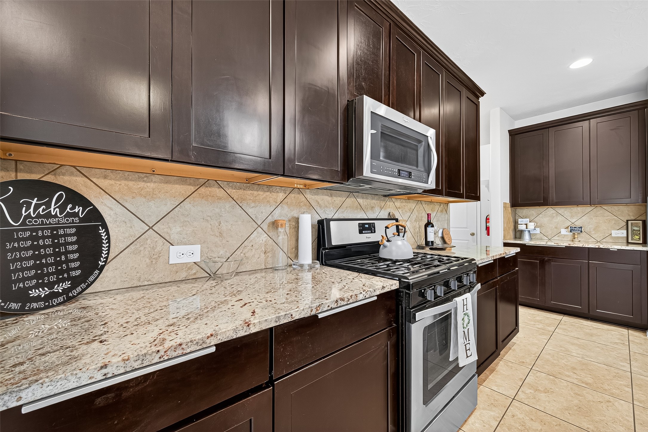 8107 Lockridge Terrace Lane Cypress, TX 77433 - Photo 19 of 50 Another look at this chef-inspired kitchen reveals an extended run of gorgeous granite countertops and deep espresso cabinetry, offering abundant prep space and storage. The stainless steel appliances blend seamlessly with the warm tones, creating a perfect balance of modern convenience and timeless charm.