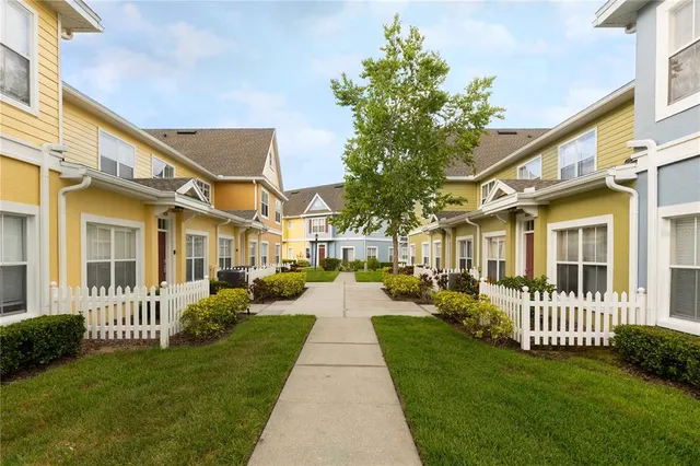 a view of a brick house with a yard plants and large trees