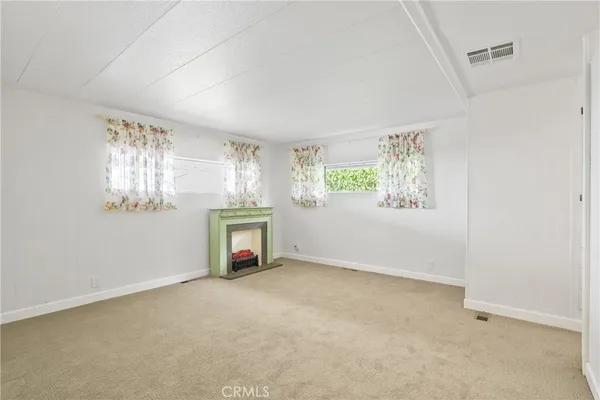 an empty room with windows and fireplace