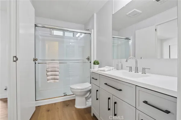 a bathroom with a granite countertop sink toilet a mirror and shower