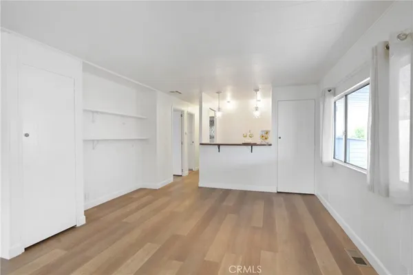 a view of a big room with wooden floor and windows