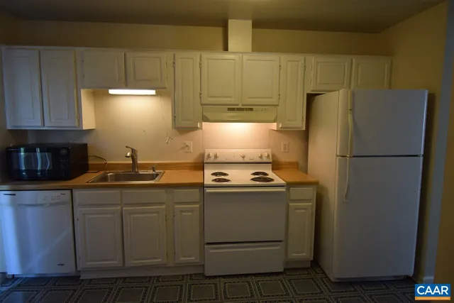 a kitchen with stainless steel appliances granite countertop a refrigerator a stove a sink and white cabinets