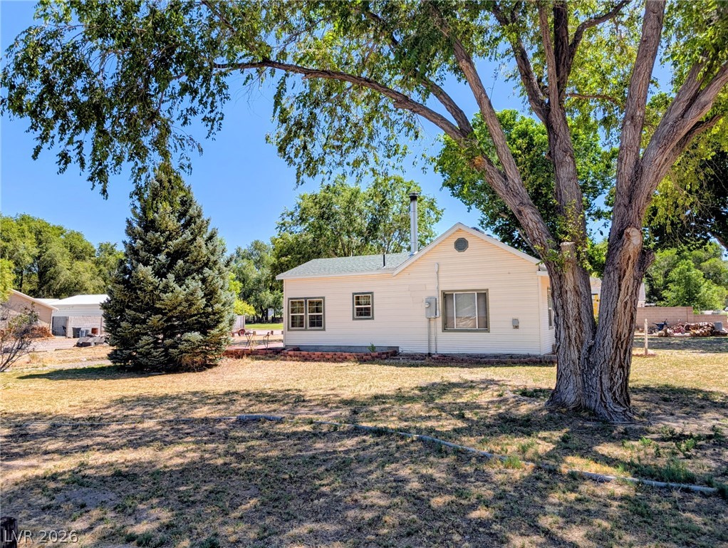 997 Phillips Street Panaca, NV 89042 - Photo 2 of 19 A quaint residence nestled amidst mature trees, offering a sense of seclusion.