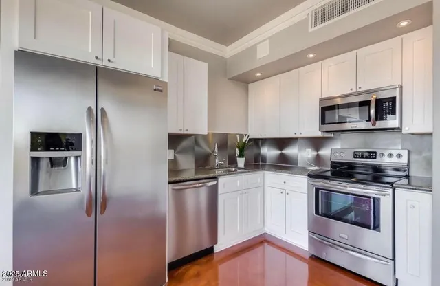 a kitchen with stainless steel appliances granite countertop grey cabinets a stove a sink and dishwasher