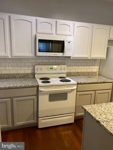 a kitchen with granite countertop white cabinets and white appliances