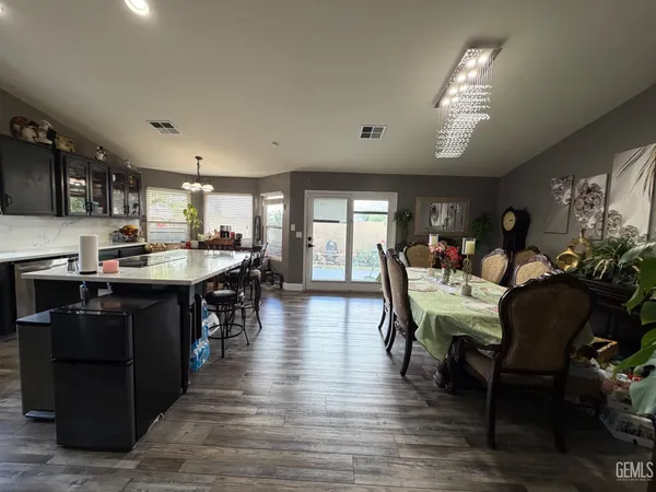 a kitchen with stainless steel appliances granite countertop a stove top oven a sink dishwasher a dining table and chairs with wooden floor