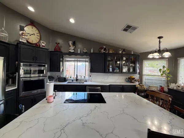 a kitchen with granite countertop a refrigerator and a stove top oven