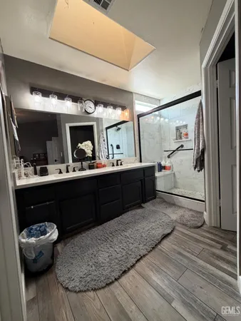 a bathroom with a granite countertop sink a mirror and shower