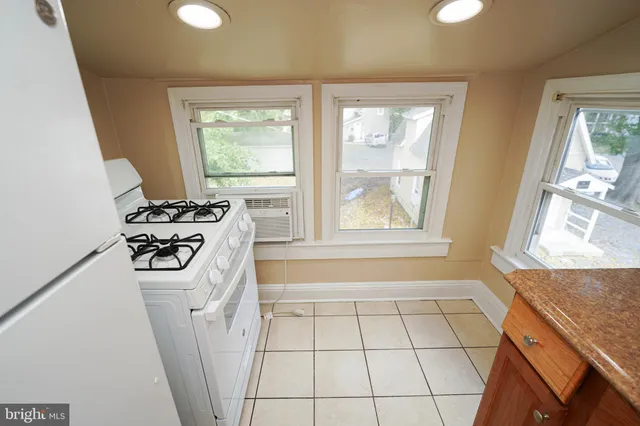a view of a refrigerator in kitchen and an empty room