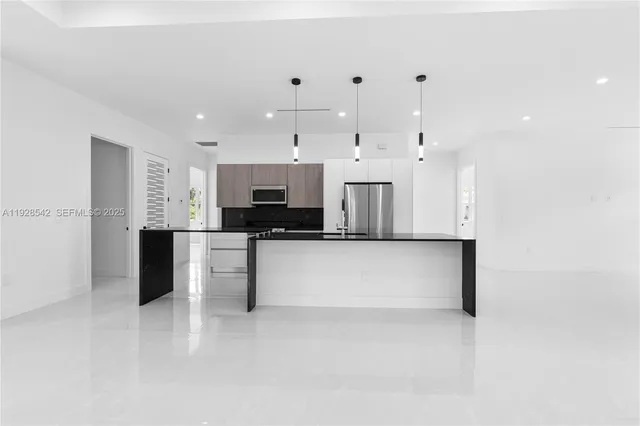 a large white kitchen with kitchen island a sink stainless steel appliances and cabinets