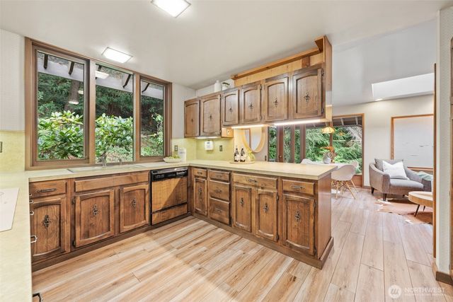 a kitchen with stainless steel appliances granite countertop a stove a sink dishwasher and wooden cabinets with wooden floor