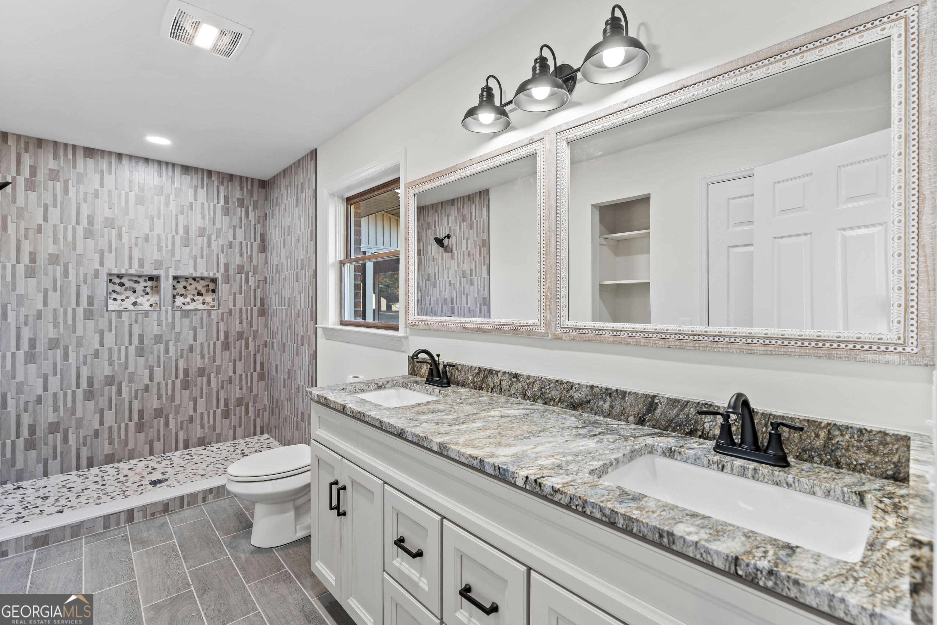 6421 Holly Springs Road Clermont, GA 30527 - Photo 32 of 58 a bathroom with a granite countertop toilet a sink and a mirror