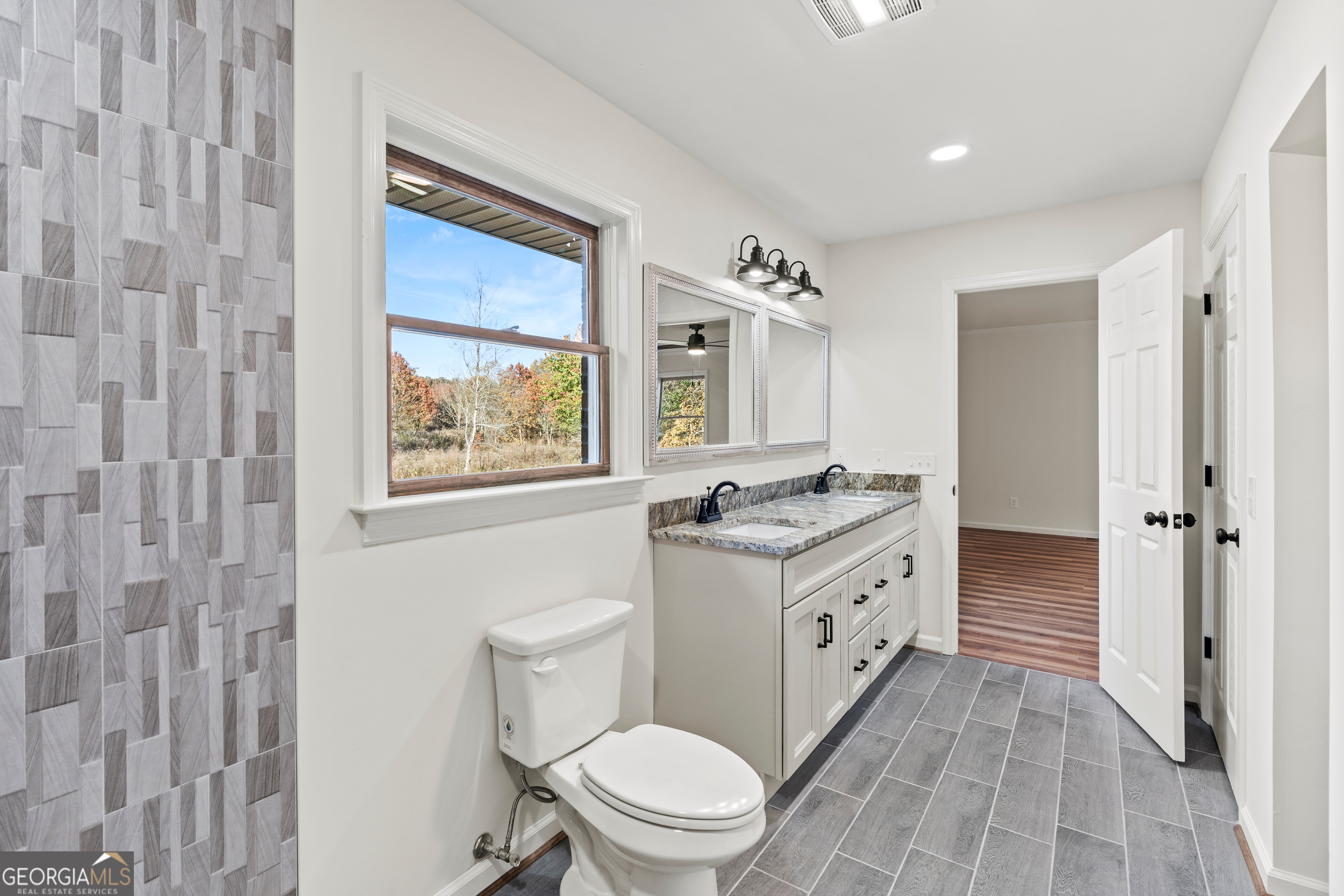 6421 Holly Springs Road Clermont, GA 30527 - Photo 34 of 58 a spacious bathroom with a granite countertop toilet a sink and a mirror
