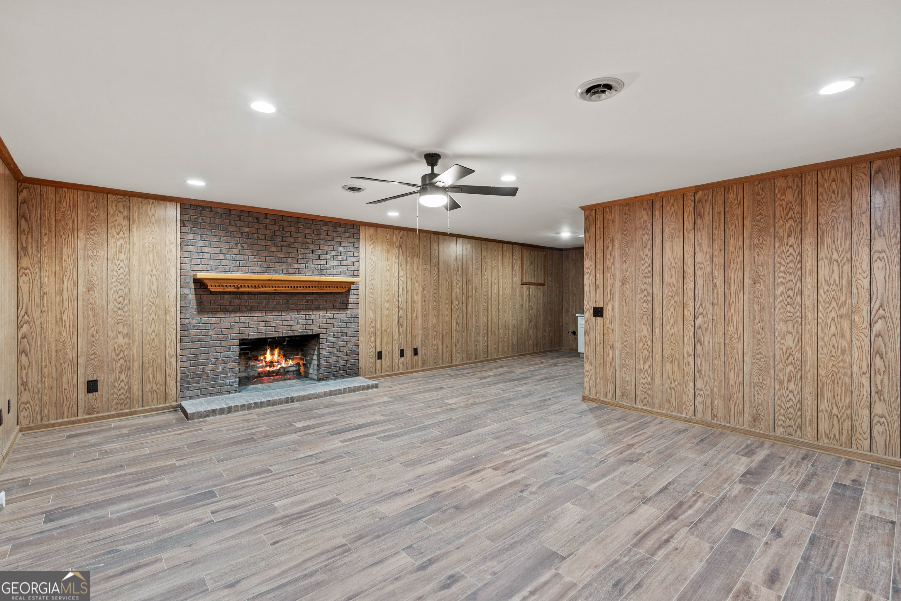 6421 Holly Springs Road Clermont, GA 30527 - Photo 39 of 58 an empty room with wooden floor fireplace and windows