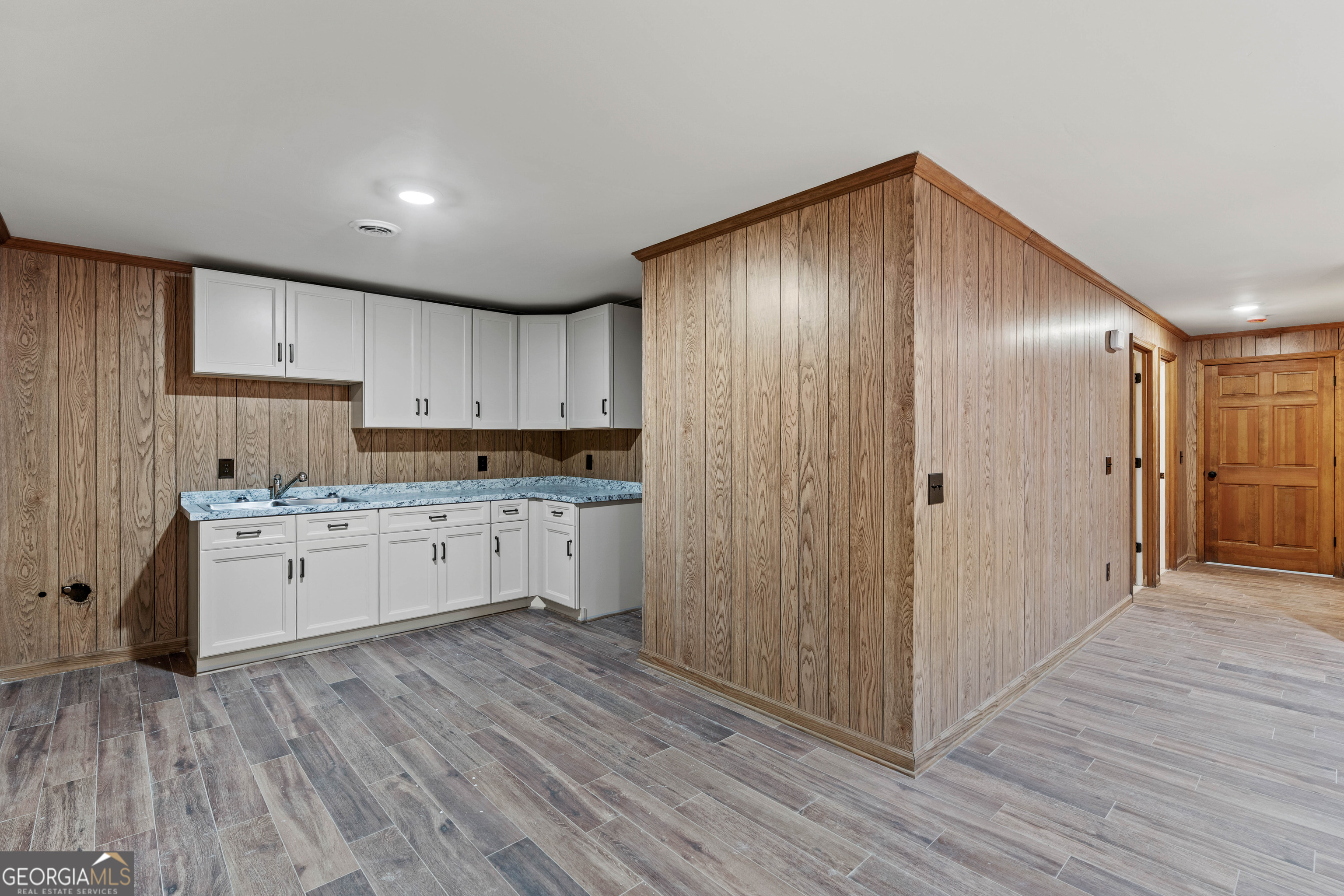 6421 Holly Springs Road Clermont, GA 30527 - Photo 40 of 58 a kitchen with cabinets wooden floor and stainless steel appliances