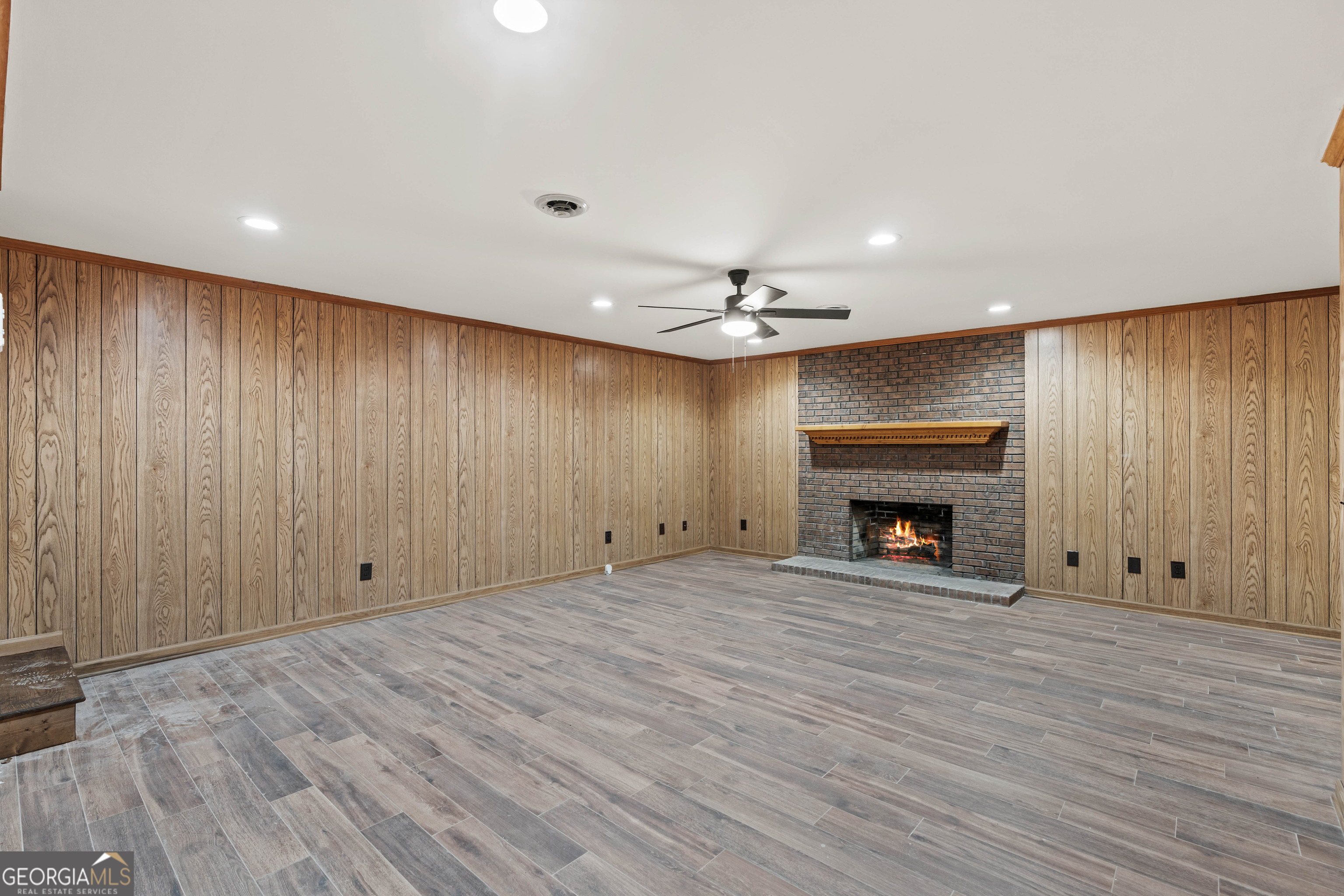 6421 Holly Springs Road Clermont, GA 30527 - Photo 44 of 58 an empty room with windows fireplace and wooden floor