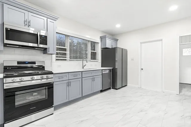 a kitchen with stainless steel appliances a stove microwave and refrigerator