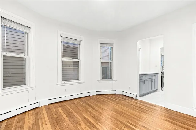 an empty room with a wooden floor and windows