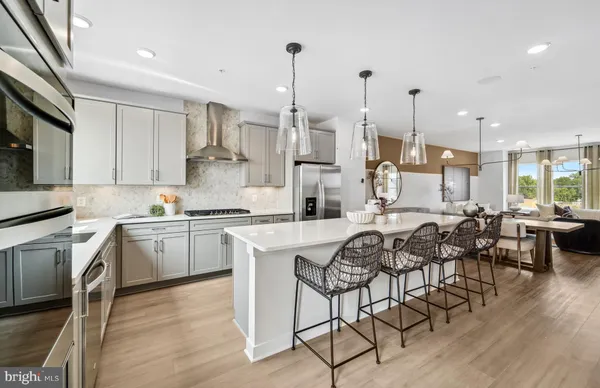 a kitchen with stainless steel appliances granite countertop a refrigerator a oven a sink a dining table and chairs with wooden floor