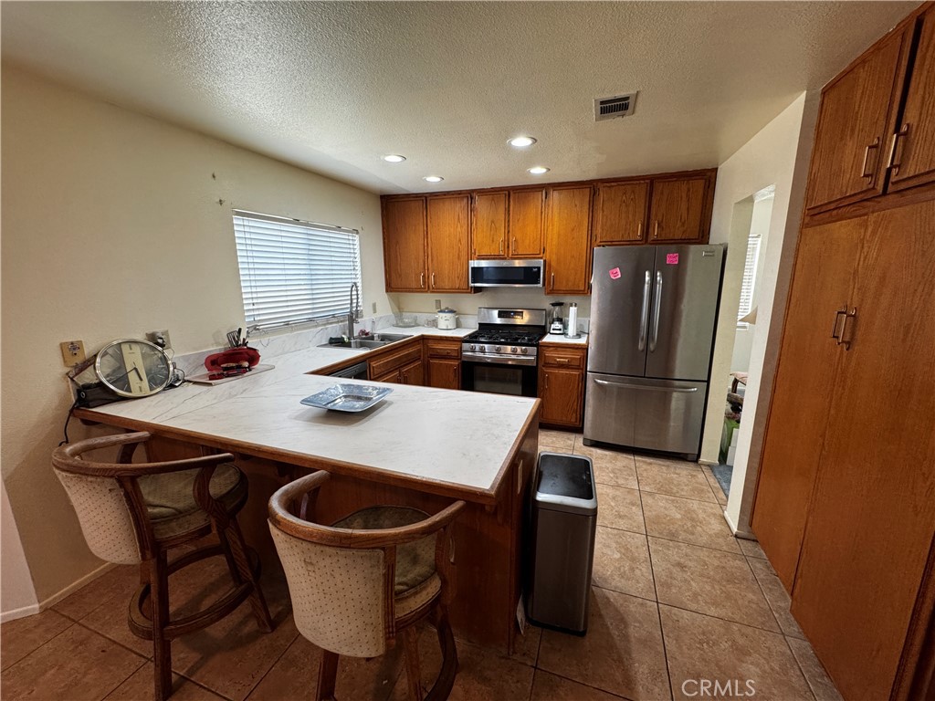 935 West Wabash Street Rialto, CA 92376 - Photo 12 of 17 a kitchen with stainless steel appliances a table chairs and refrigerator
