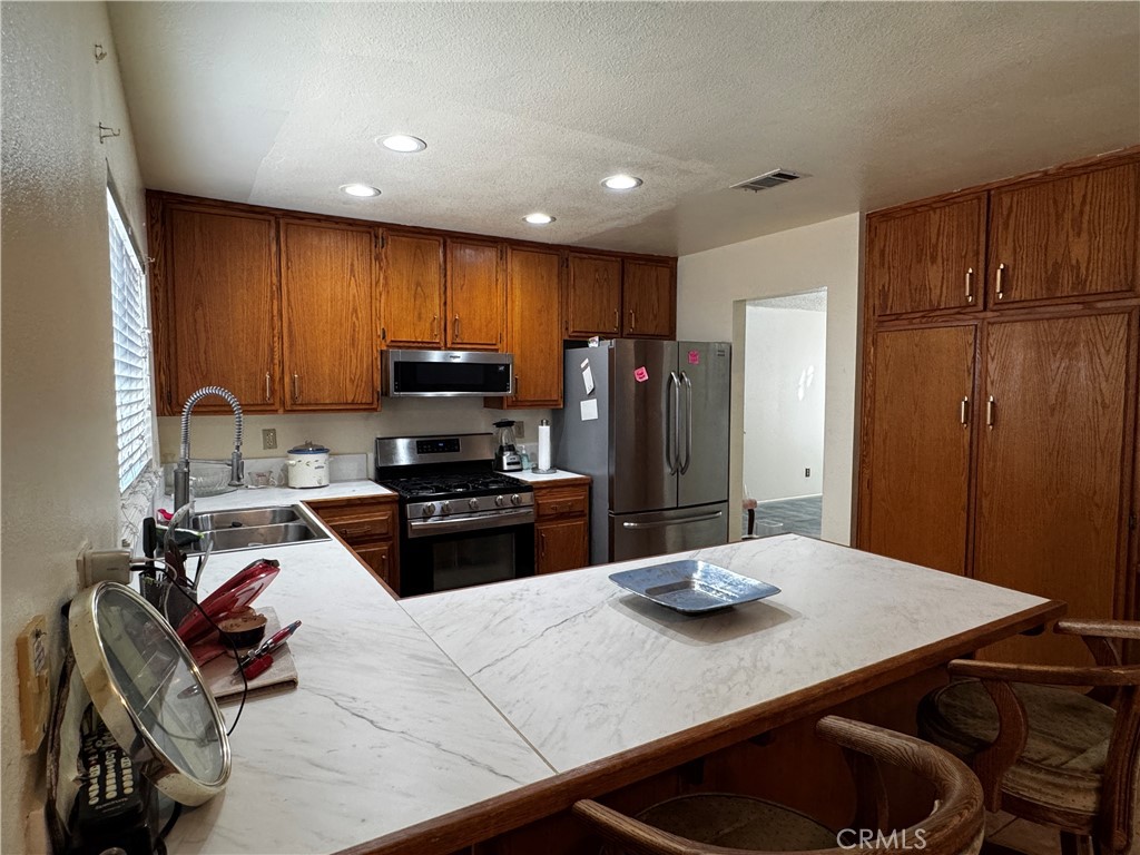 935 West Wabash Street Rialto, CA 92376 - Photo 13 of 17 a kitchen with stainless steel appliances a dining table chairs and refrigerator