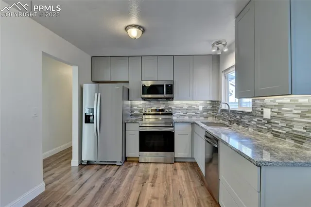 a kitchen with granite countertop a stove top oven and refrigerator