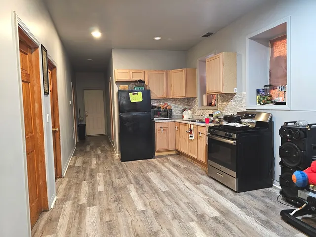 a kitchen with stainless steel appliances granite countertop a refrigerator a sink dishwasher a stove and white countertops with wooden floor