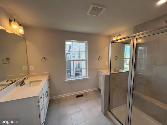 a spacious bathroom with a double vanity sink a mirror and a shower