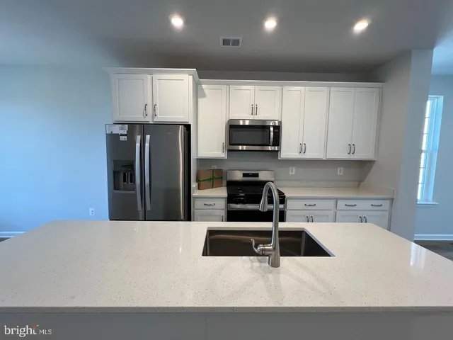 a kitchen with stainless steel appliances a refrigerator a sink a stove a microwave and cabinets