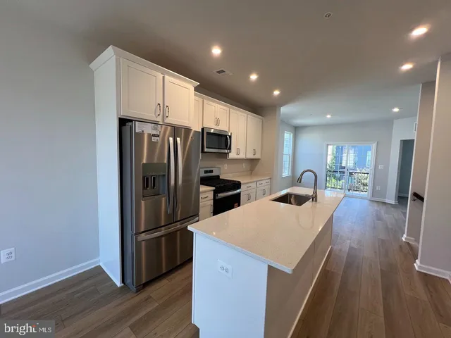 a kitchen with a refrigerator a stove top oven and wooden floor