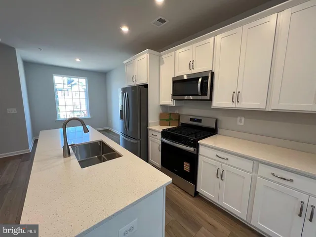 a kitchen with stainless steel appliances a stove a sink a microwave a refrigerator a counter space and cabinets